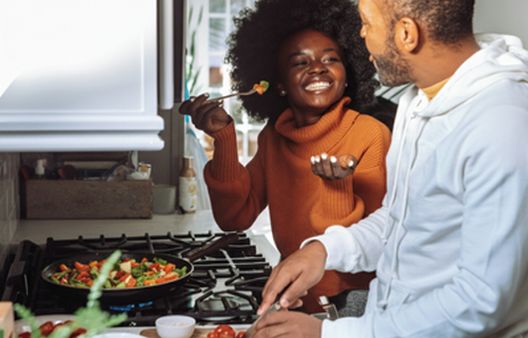 Couple cooking healthy stir fry vegetables together in their kitchen