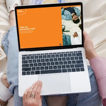 Woman sat on bed looking at laptop