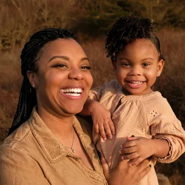 Smiling woman holding young laughing daughter in her arms