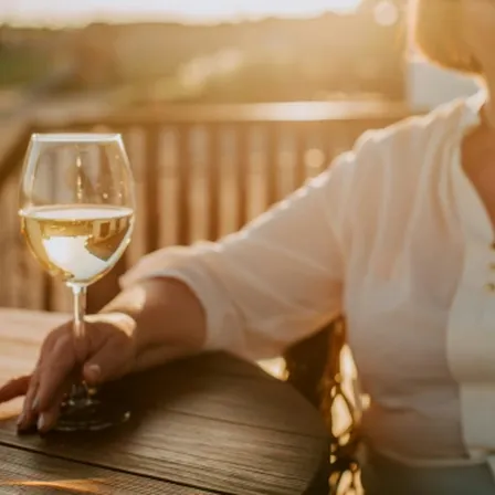 Woman sat at outside table holding white wine glass