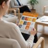 Person sitting on chair reading breast check flyer orange and grey