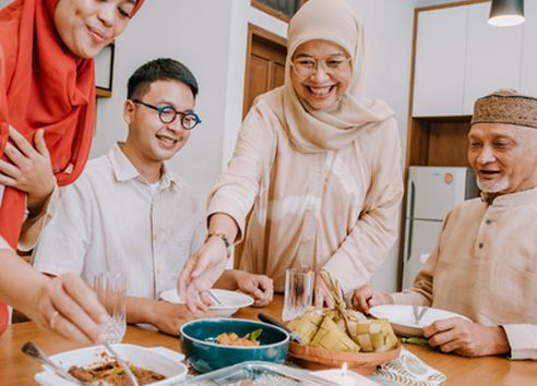 Muslim family gathered around the dinner table smiling