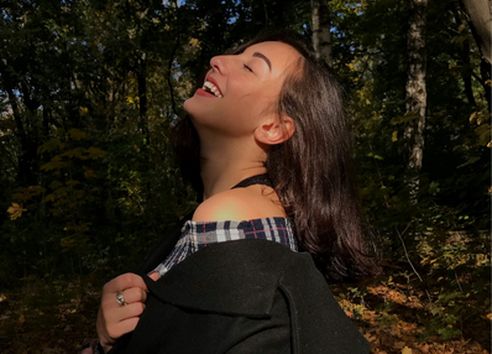 Woman with eyes closed soaking up sunlight on her face and smiling