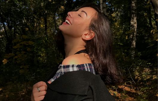 Woman with eyes closed soaking up sunlight on her face and smiling