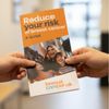 Person holding reduce your risk flyer orange