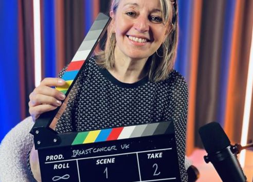 Breast Cancer CEO in podcast studio holding clapper board