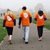 3 people with their backs to the camera on a sponsored walk, wearing Breast Cancer UK T-shirts