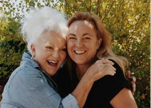 Older mother hugging adult daughter and laughing