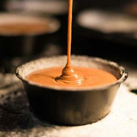 Orange sauce being poured into ceramic dish