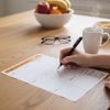 hand filling out wellness meal planner sheet on kitchen table