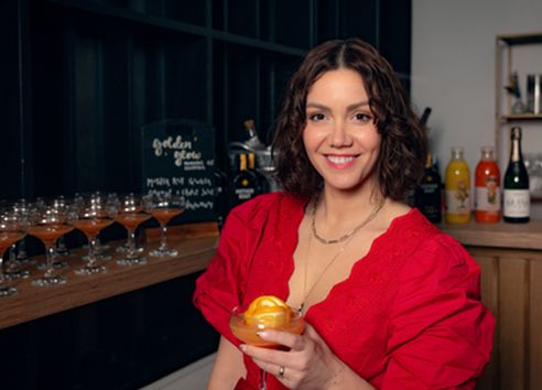 Headshot of Camille Vidal holding her Golden Glow cocktail at Breast Cancer UK Full Supper Club Launch